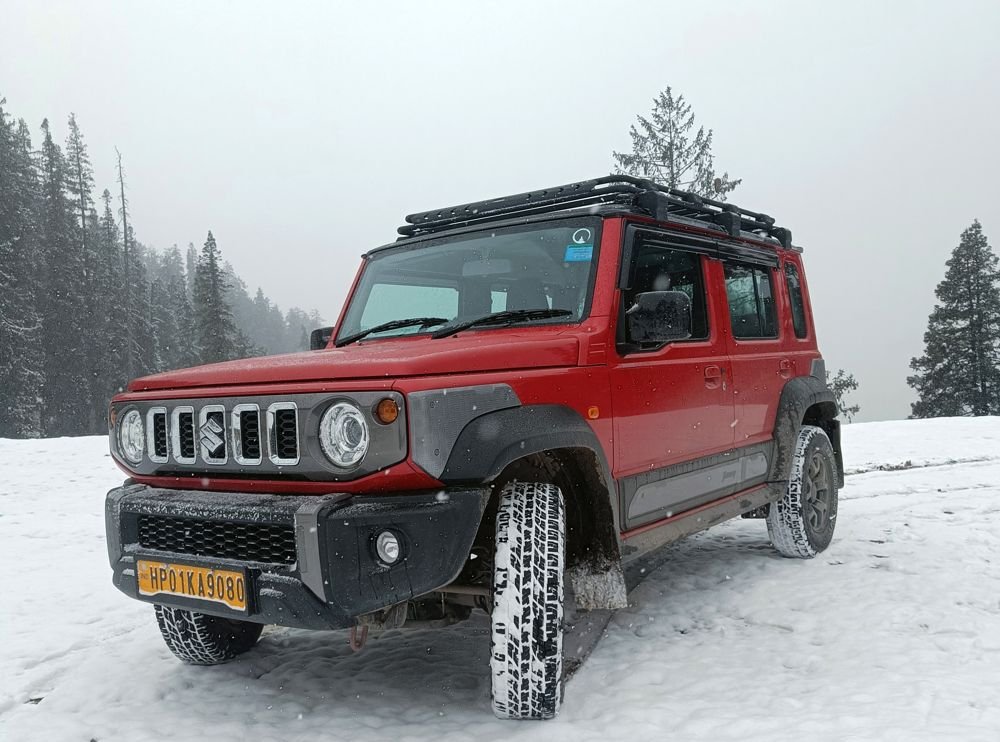 Red 4x4 Jimny cab with roof rack in snow near Manali